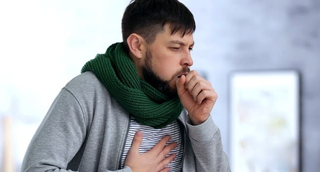 Кашляющий мужчина с толстым шарфом на шее